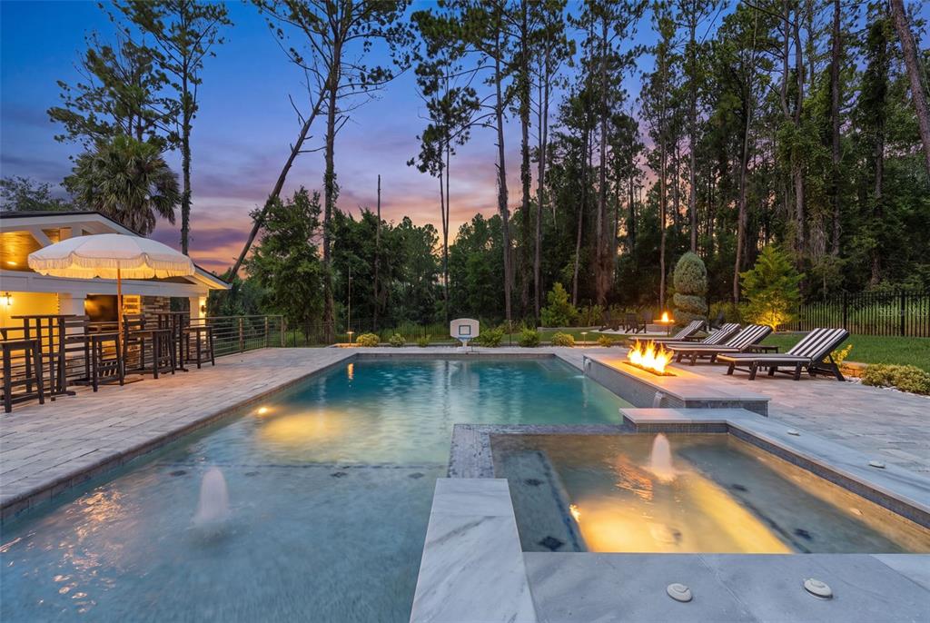 A backyard swimming pool with a spa, fire feature, and patio at dusk — 20085 ENGLISH WALNUT PLACE, BROOKSVILLE, FL