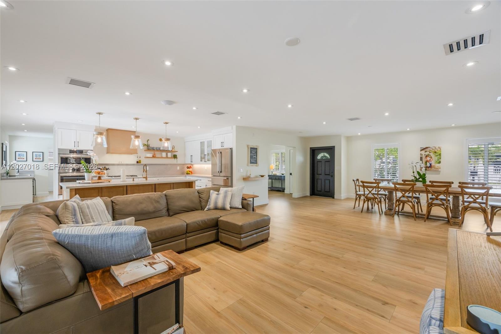 An open-concept living area features a kitchen, dining space, and sectional sofa on wood floors — 4730 SW 89th Ave, Miami FL 33165, MIAMI, FL