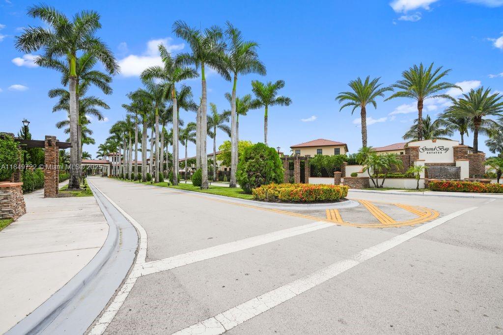 A paved entrance road leads to the gated community of Grand Bay Estates with palm trees — 10016 NW 89th Ter, Doral FL 33178, DORAL, FL