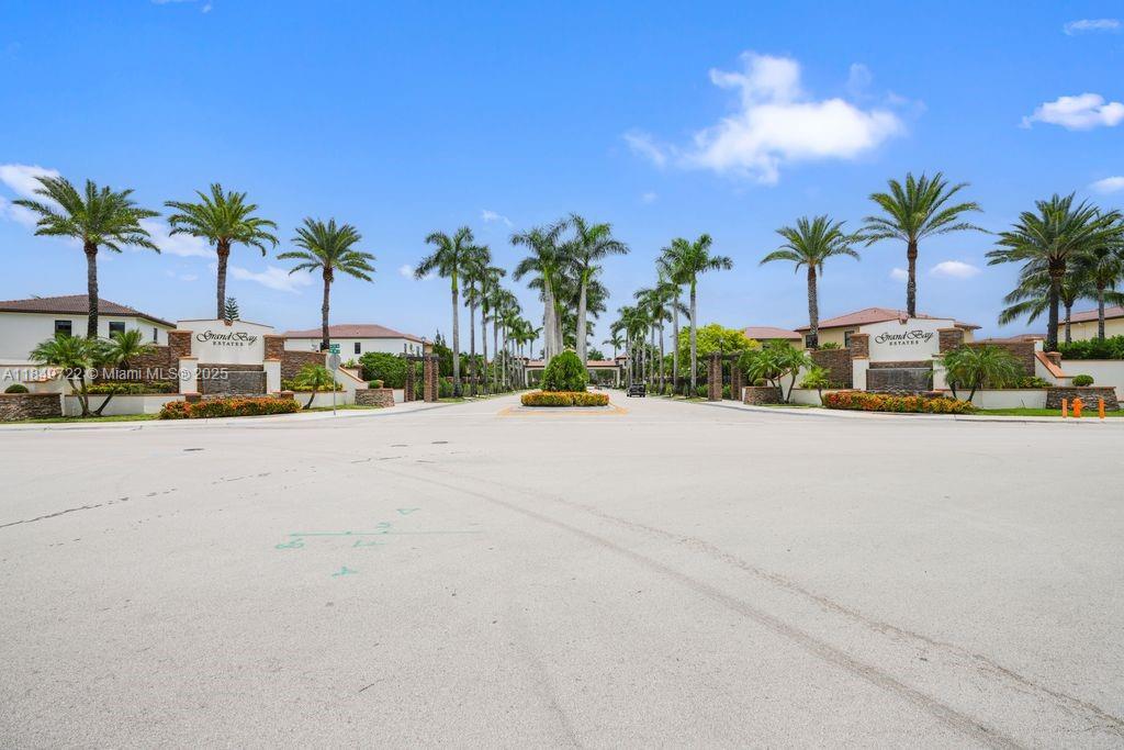 The entrance to Grand Bay Estates features a paved road lined with palm trees — 10016 NW 89th Ter, Doral FL 33178, DORAL, FL