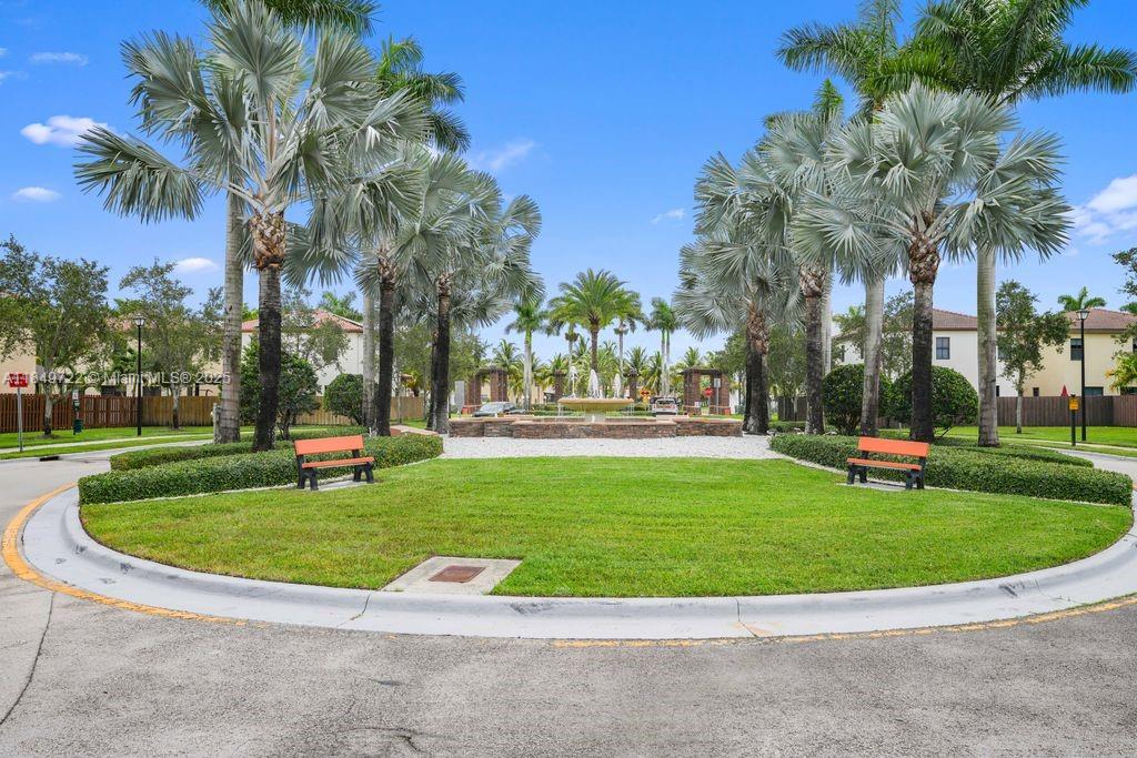 A circular grassy courtyard features a central fountain, palm trees, and two orange benches — 10016 NW 89th Ter, Doral FL 33178, DORAL, FL