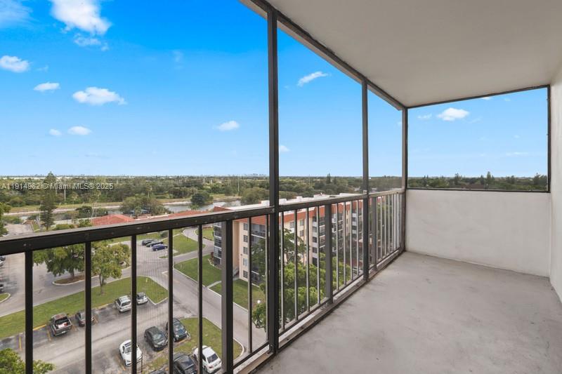 A screened-in balcony overlooks a parking lot, green space, and a distant canal — 4174 Inverrary Dr # 902, Lauderhill FL 33319, LAUDERHILL, FL