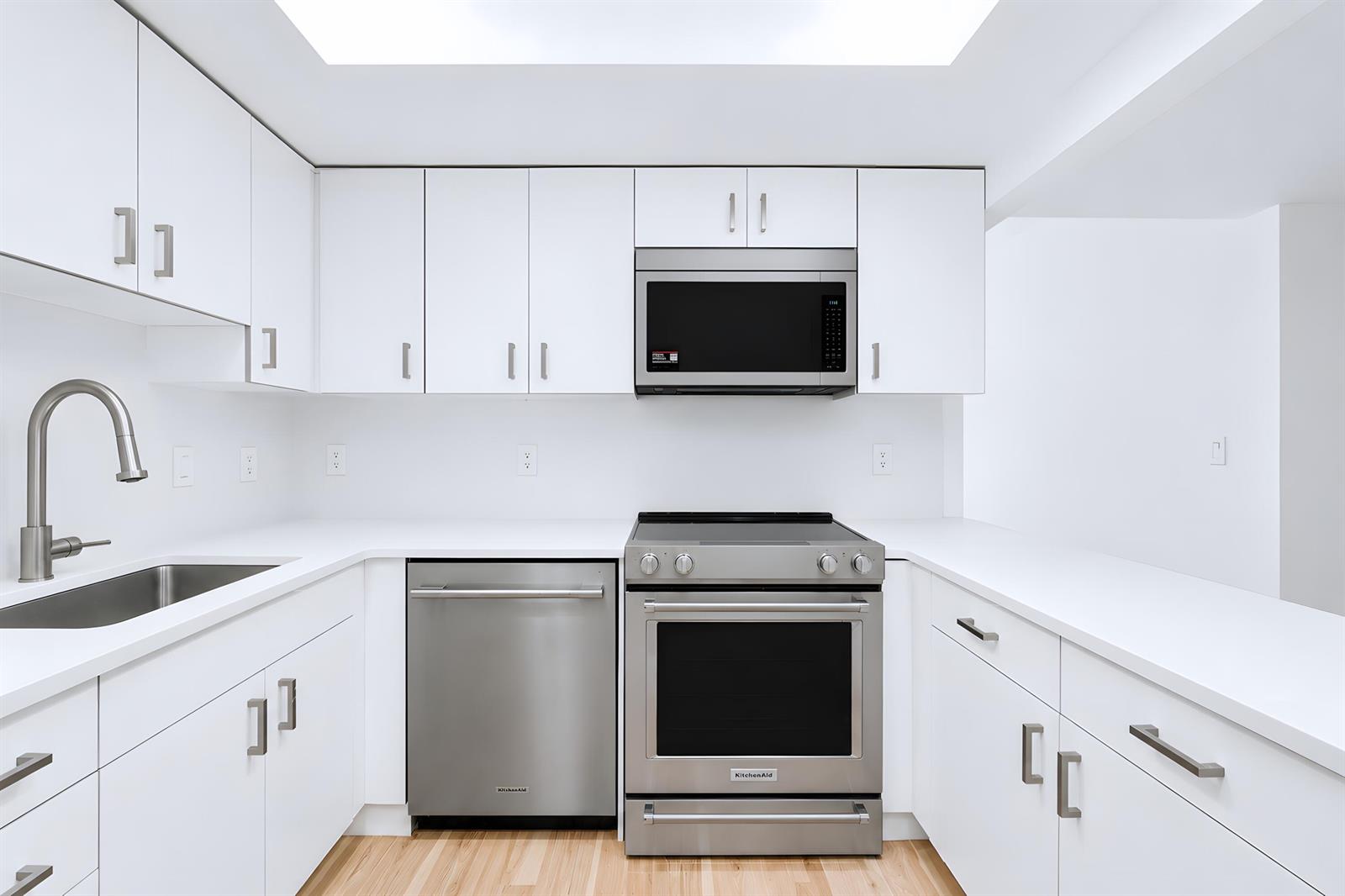 A modern kitchen features white cabinetry, stainless steel appliances, and light wood flooring — 3230 S Ocean Boulevard # 410, Palm Beach FL 33480, PALM BEACH, FL