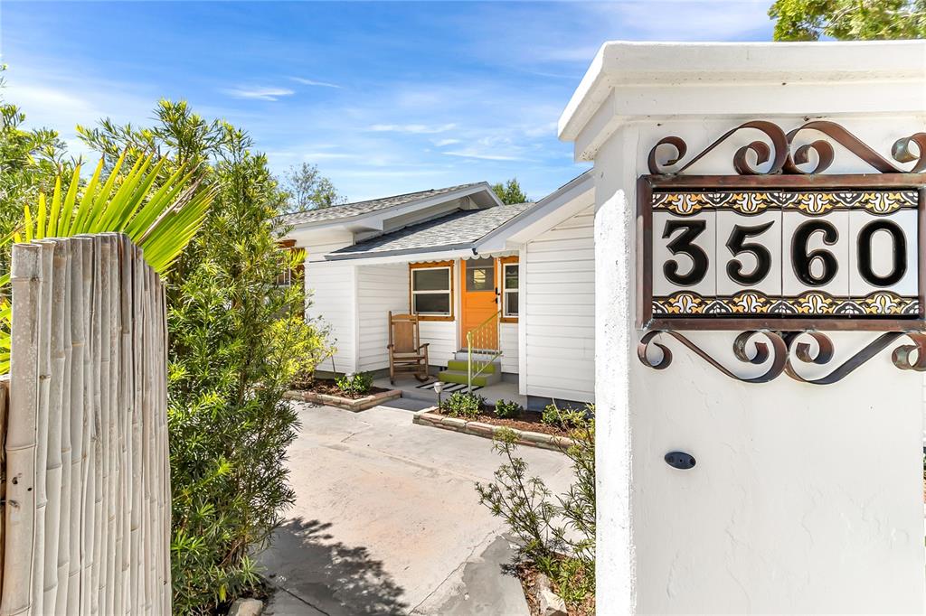 A white house with a yellow front door is viewed past a decorative address pillar — 3560 MARTIN AVENUE, MOUNT DORA, FL