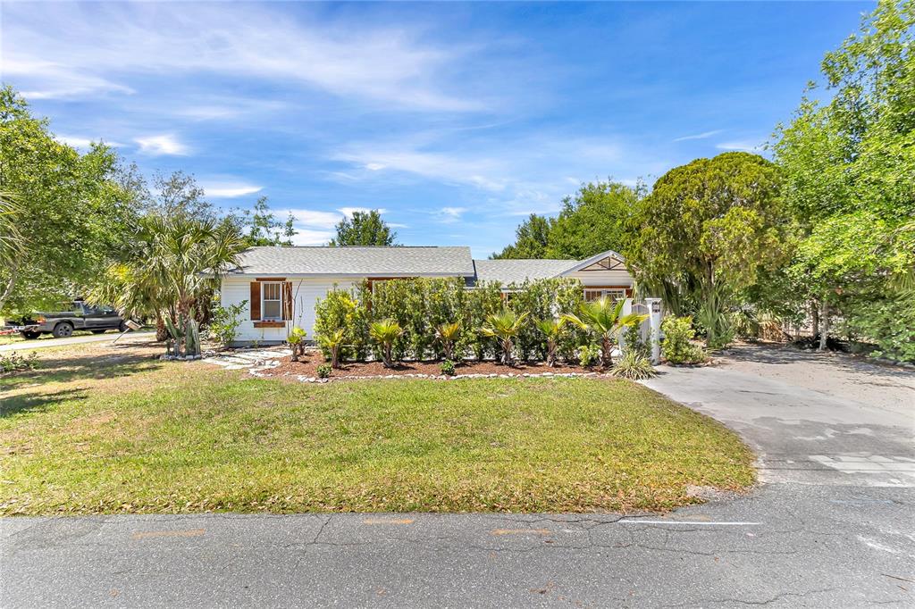 A single-story white house with a shingled roof sits behind a row of shrubs — 3560 MARTIN AVENUE, MOUNT DORA, FL
