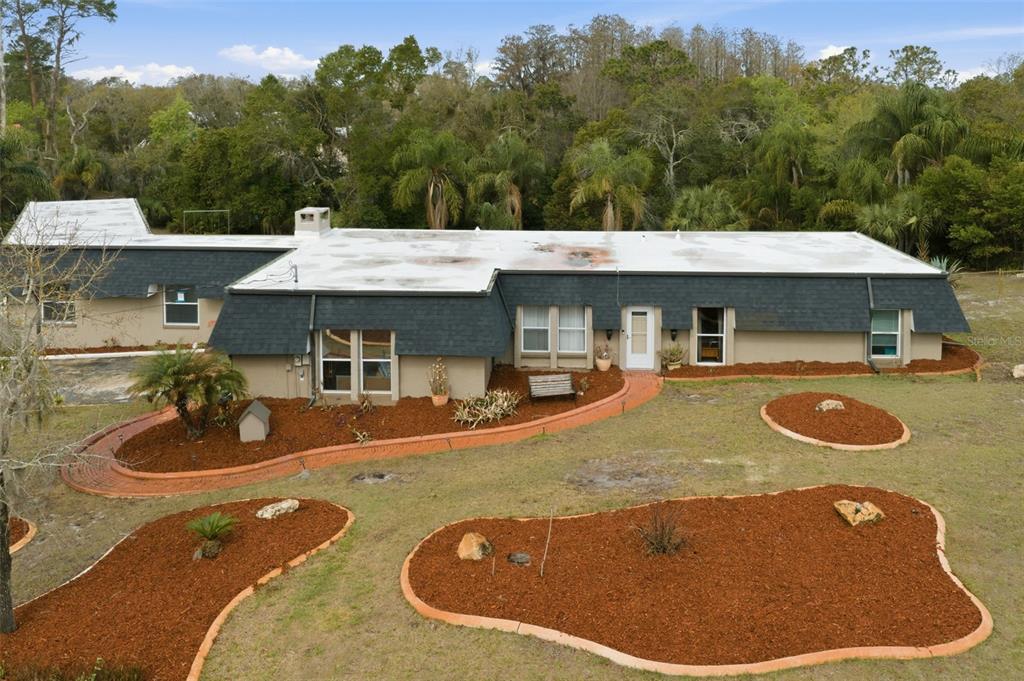 An aerial view shows a single-story house with a flat roof and dark shingled mansard siding — 7815 TANGLEWOOD DRIVE, NEW PORT RICHEY, FL