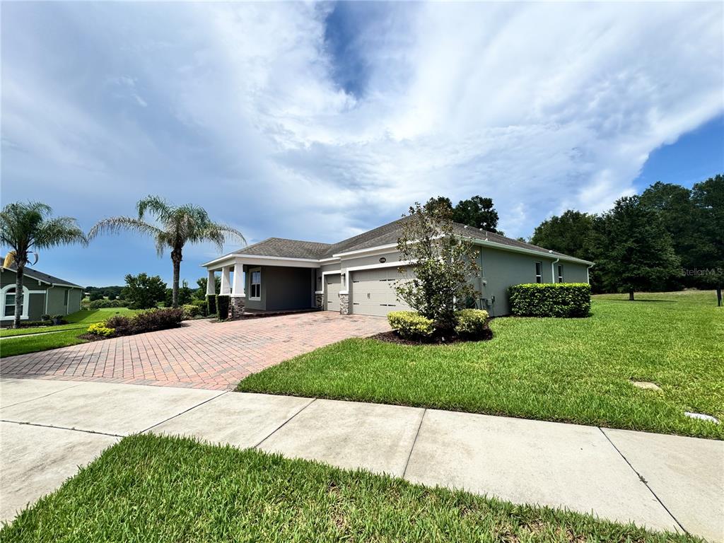 A single-story house with a brick paver driveway, a two-car garage, and a palm tree — 31936 GEOFF WAY, SORRENTO, FL