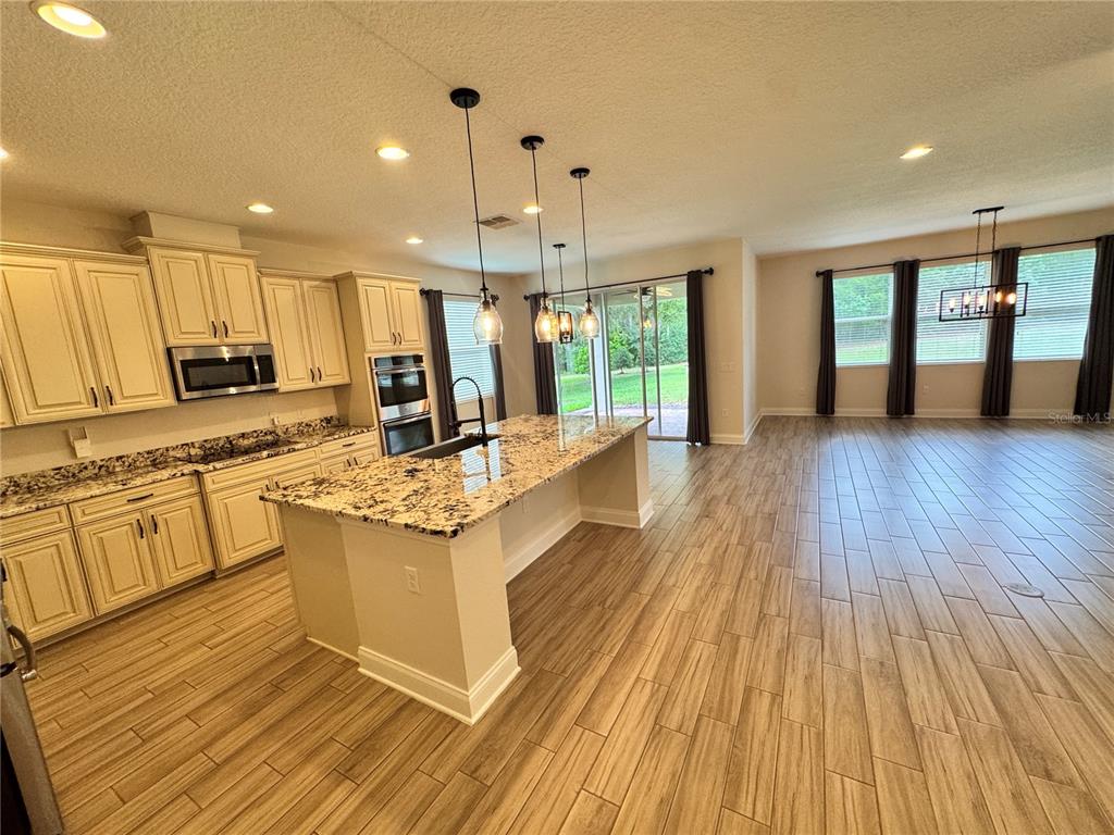 A kitchen with granite countertops and light cabinets opens into a spacious living area — 31936 GEOFF WAY, SORRENTO, FL