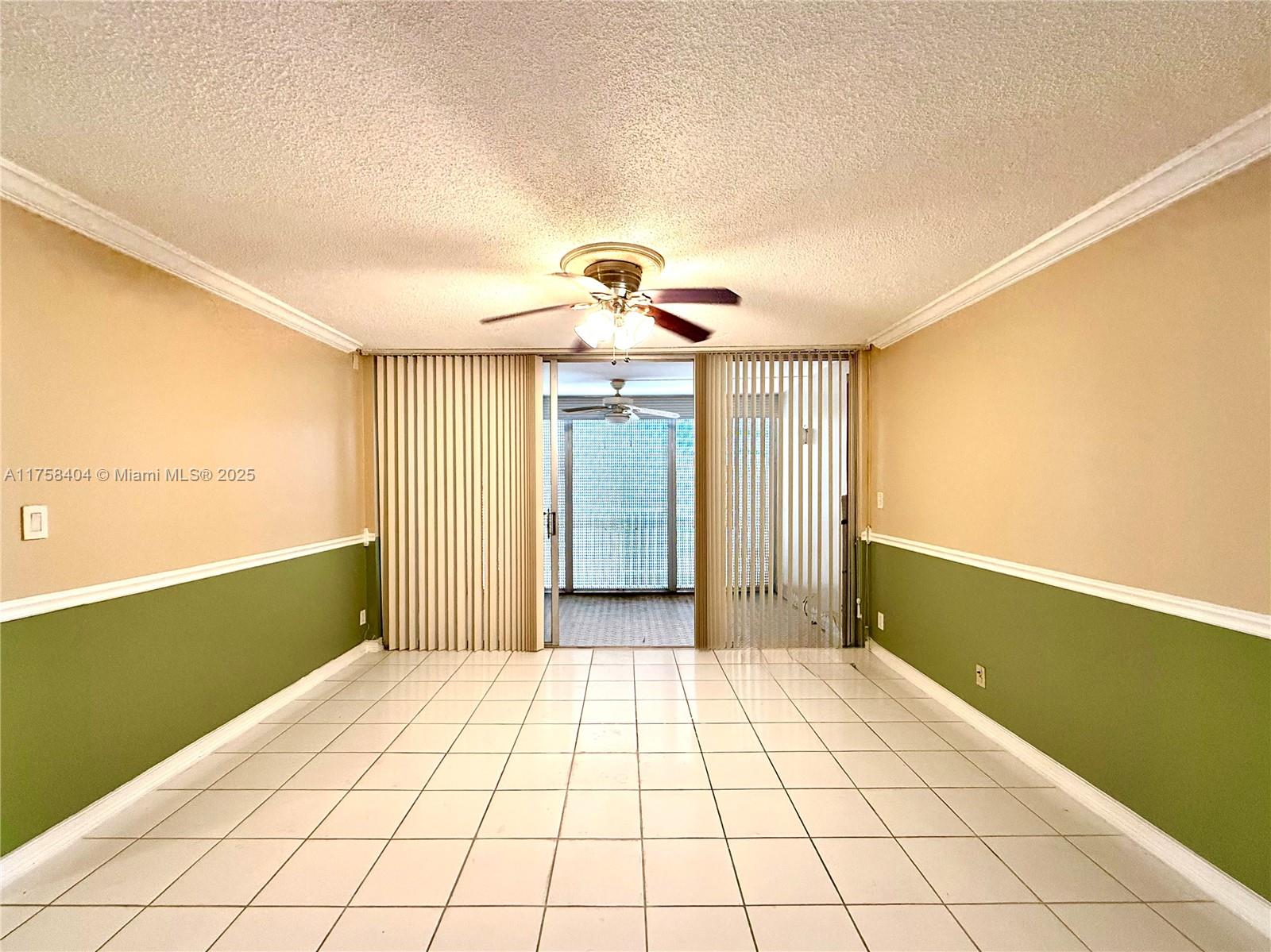 A room with white tiled floors, two-toned walls, and a ceiling fan leads to a balcony — 920 NE 199th St # 4J, Miami FL 33179, MIAMI, FL