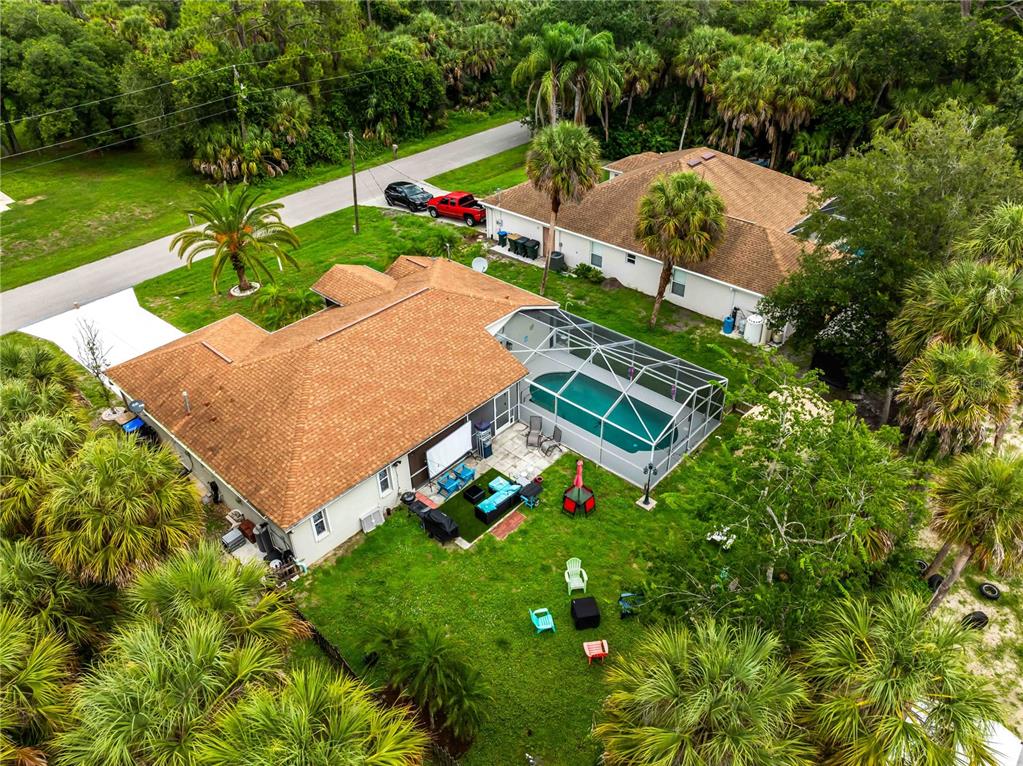 An aerial view shows a house with a brown roof, screened pool, and backyard lawn — 4243 FONSICA AVENUE, NORTH PORT, FL