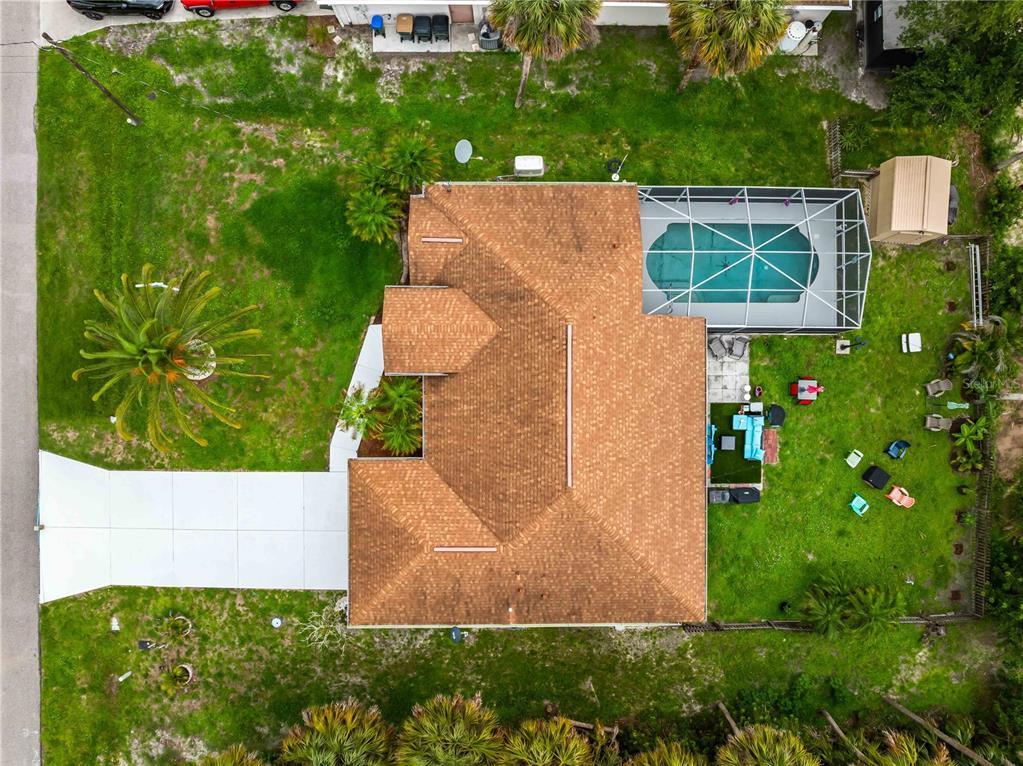 An aerial view of a house with a brown shingled roof, pool enclosure, and driveway — 4243 FONSICA AVENUE, NORTH PORT, FL