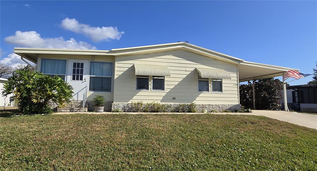 A single-story mobile home with light siding, metal window awnings, and an attached carport — 3450 N CITRUS CIRCLE UNIT GE, ZELLWOOD, FL