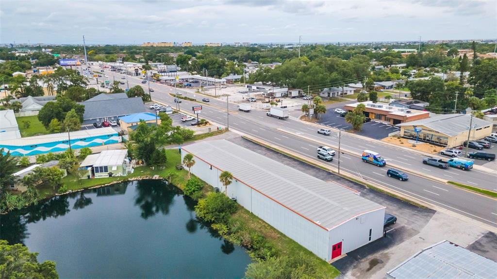 An aerial view shows a long metal warehouse building situated next to a small pond — 6581 SEMINOLE BOULEVARD, SEMINOLE, FL