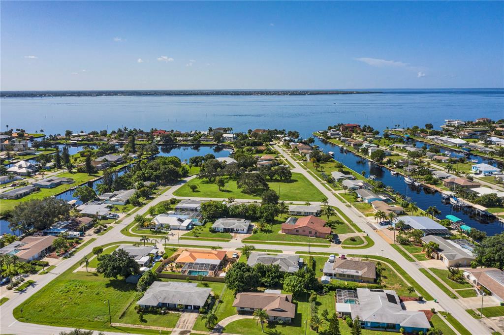 An aerial view shows a residential neighborhood with houses, canals, and a large bay — 326 WHERLEY AVENUE SE, PORT CHARLOTTE, FL
