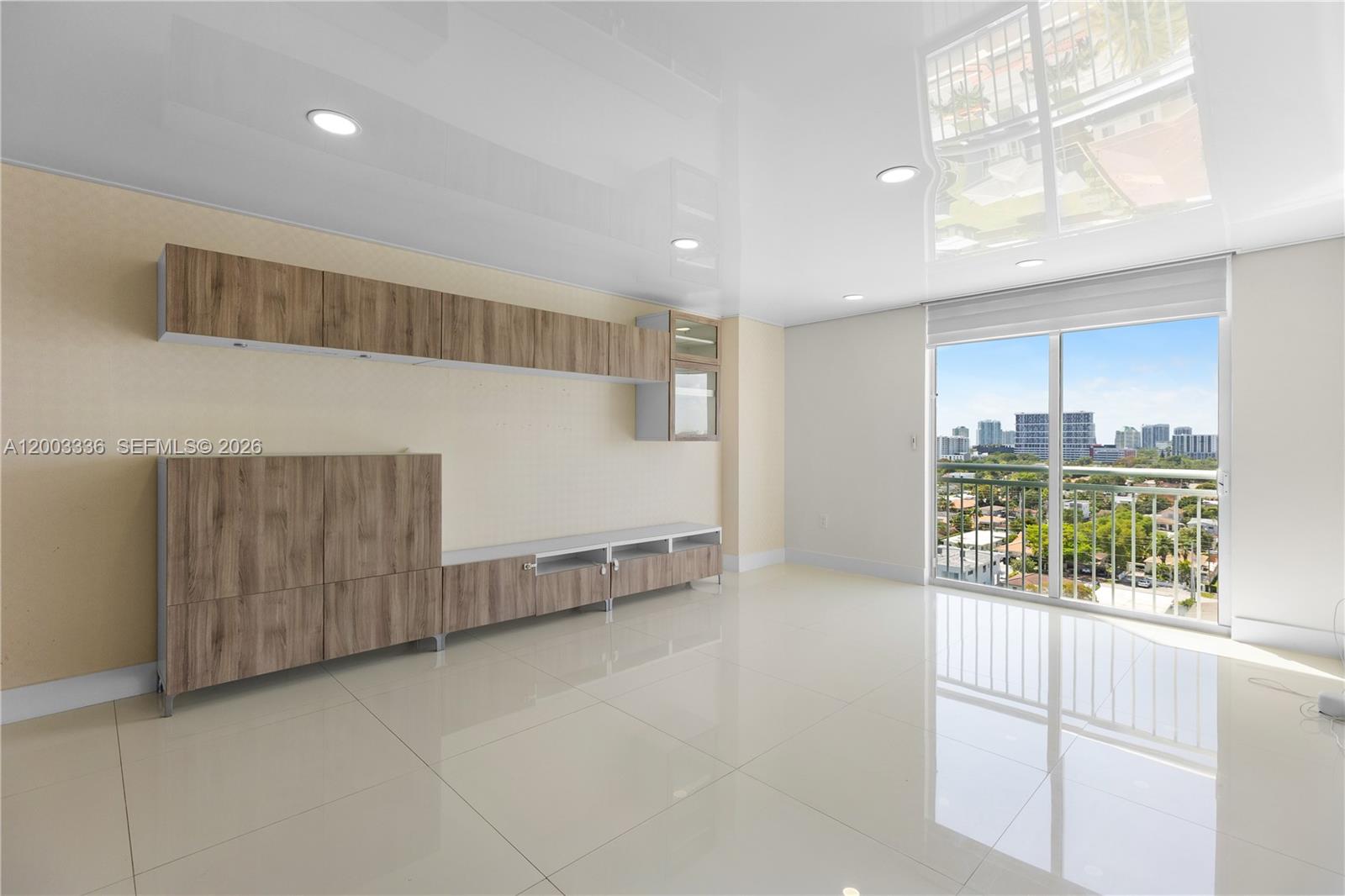 A modern living room features wood-toned cabinetry, glossy white tile floors, and a balcony view — 3000 Coral Way # 1110, Miami FL 33145, MIAMI, FL