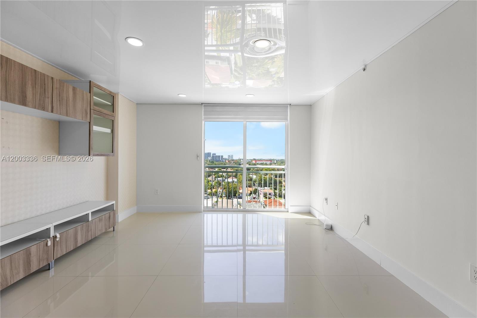A bright living room features glossy white tile floors, a reflective ceiling, and balcony access — 3000 Coral Way # 1110, Miami FL 33145, MIAMI, FL