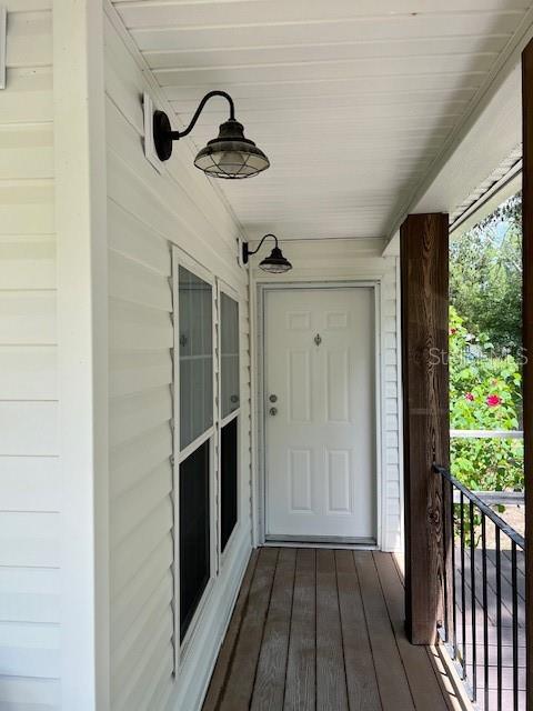 A covered porch features white siding, two wall-mounted light fixtures, and a white front door — 6850 SE 88 LANE, TRENTON, FL