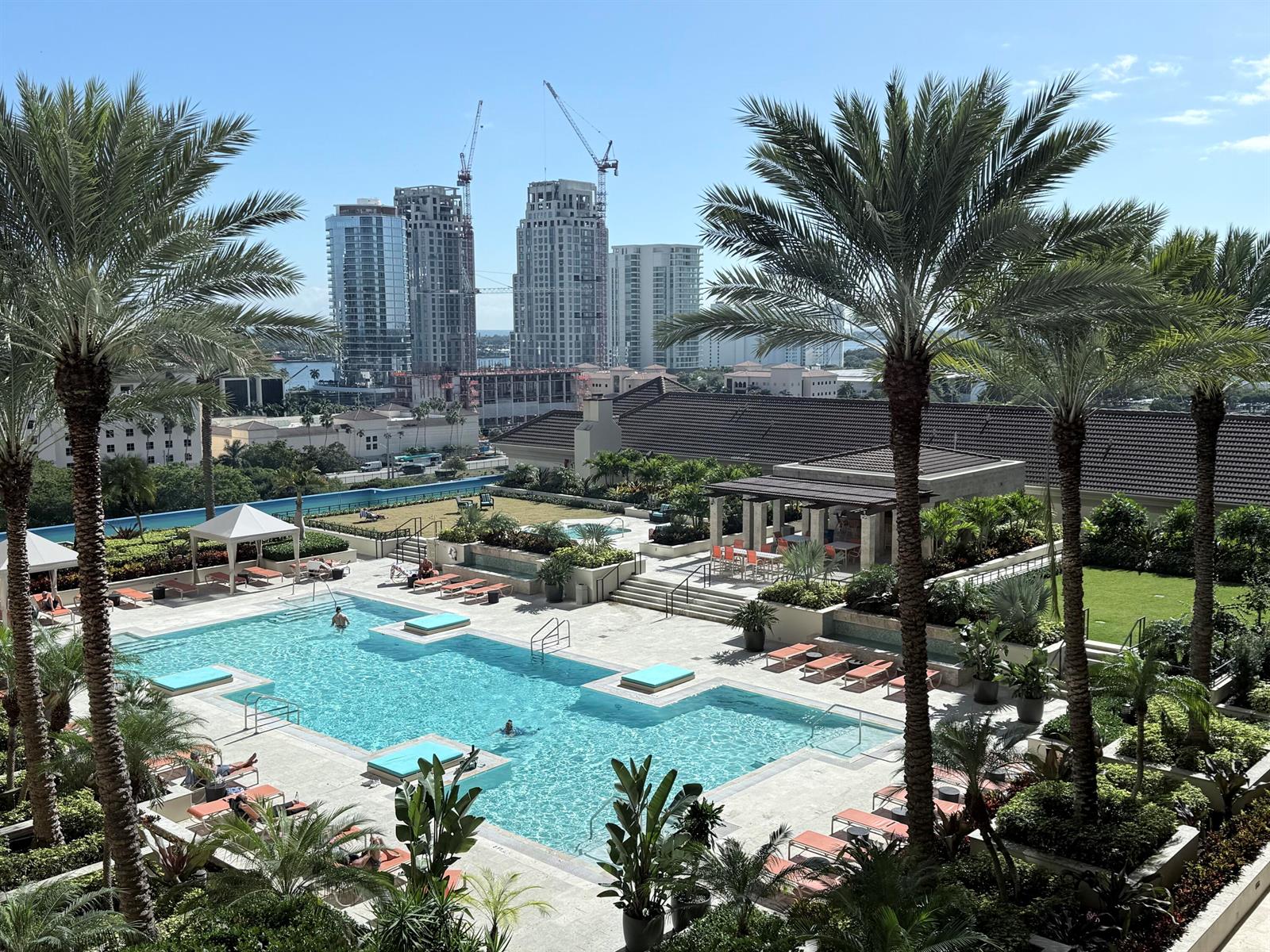 An elevated view of a swimming pool deck surrounded by palm trees and city buildings — 550 Okeechobee Boulevard # 1201, West Palm Beach FL 33401, WEST PALM BEACH, FL