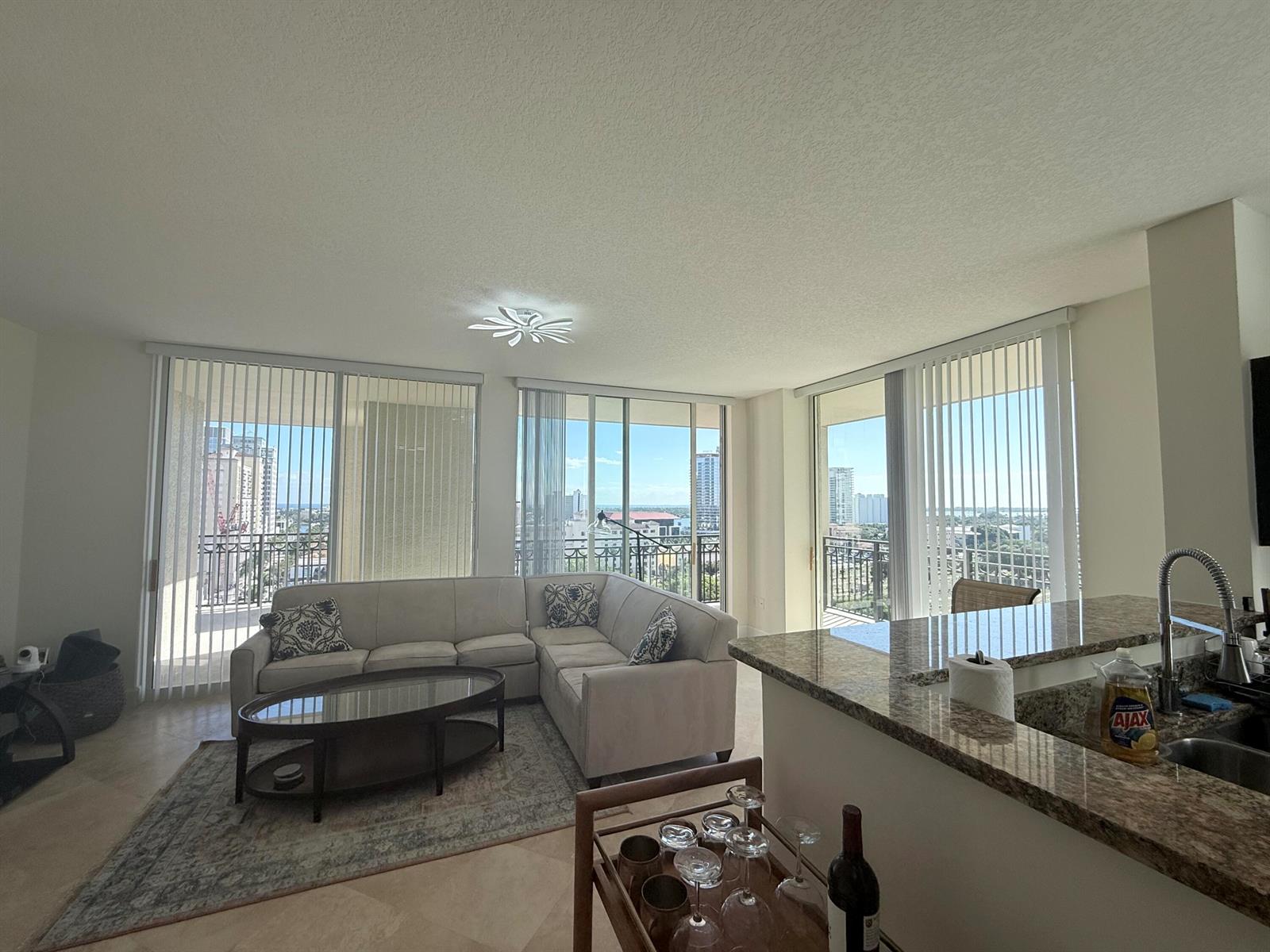 A living room with a sectional sofa, coffee table, and floor-to-ceiling windows overlooking a city — 550 Okeechobee Boulevard # 1201, West Palm Beach FL 33401, WEST PALM BEACH, FL