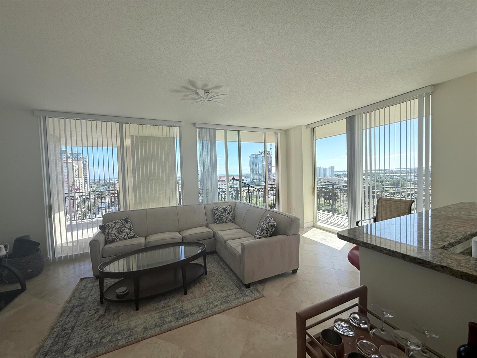 A living room features a sectional sofa, glass coffee table, and floor-to-ceiling windows with views — 550 Okeechobee Boulevard # 1201, West Palm Beach FL 33401, WEST PALM BEACH, FL
