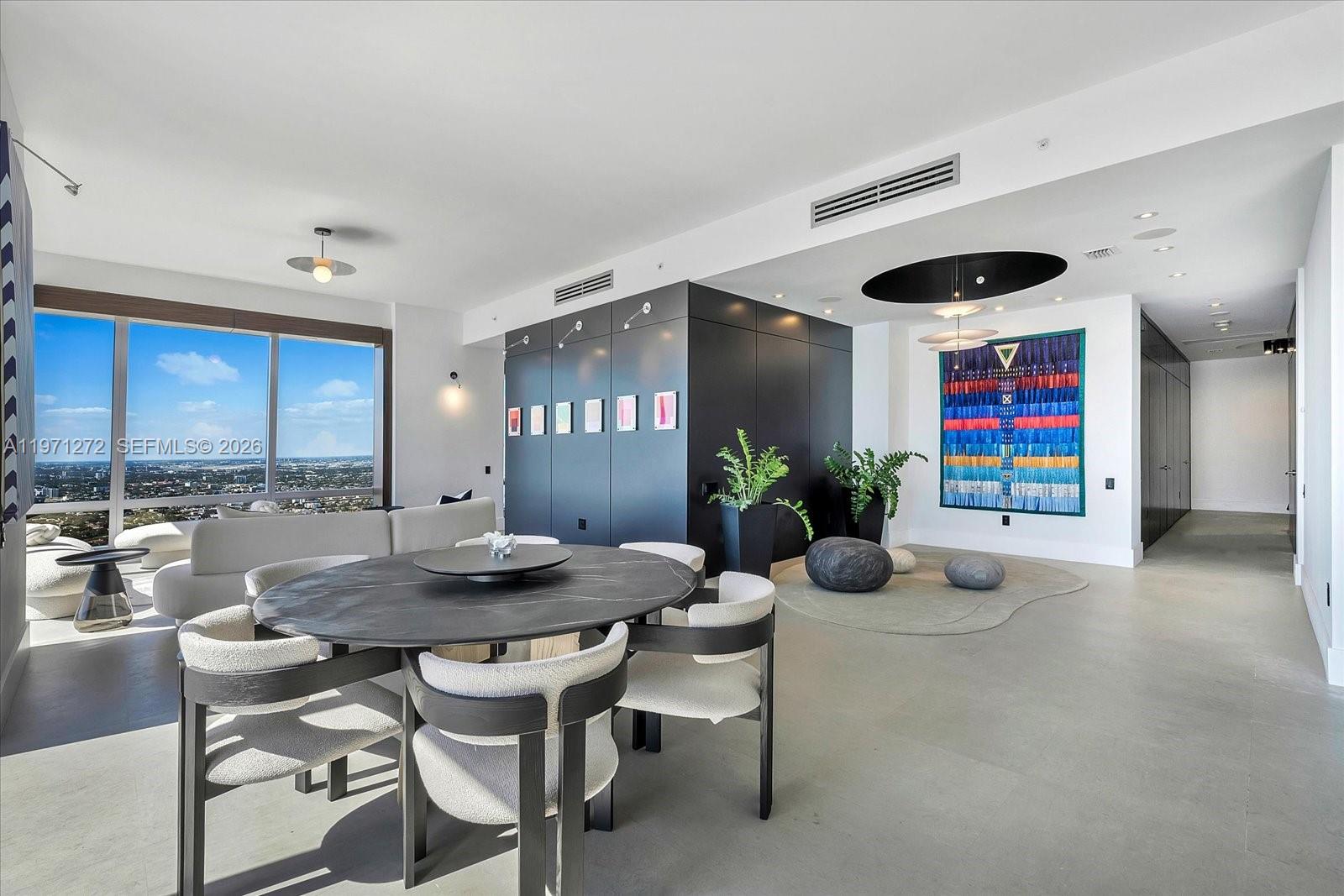 A modern dining area features a round black table, upholstered chairs, and a large tapestry — 1425 Brickell Ave, Miami FL 33131, MIAMI, FL
