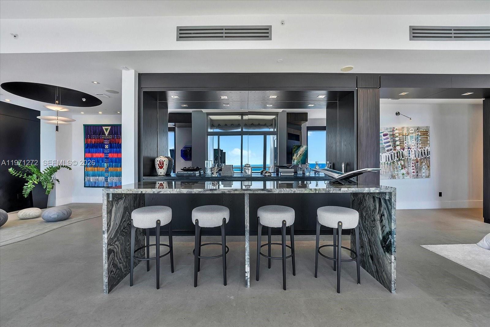 A modern kitchen island with four bar stools sits in front of a dark cabinetry wall — 1425 Brickell Ave, Miami FL 33131, MIAMI, FL