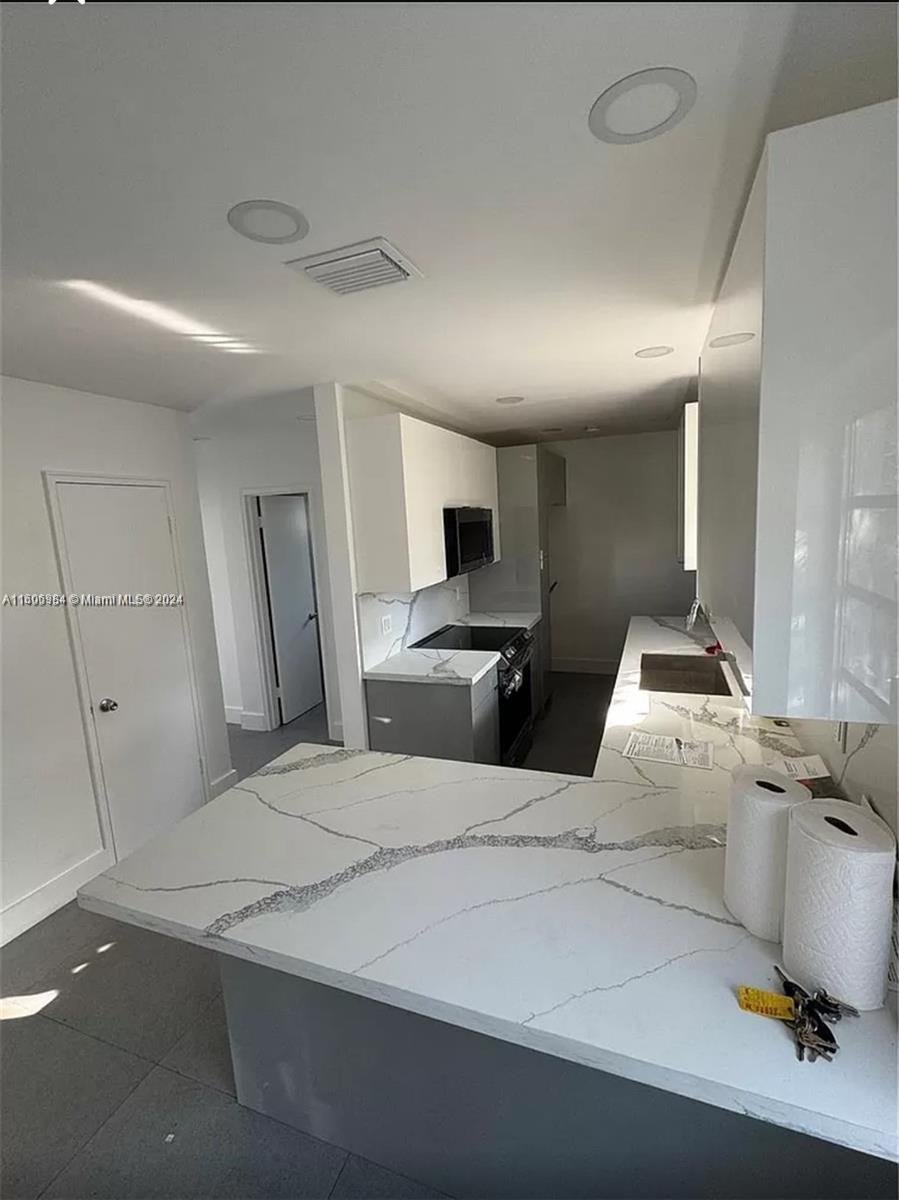 A modern kitchen features white marble-patterned countertops, grey lower cabinets, and white upper cabinets — 110 NW 120 Ter # 0, North Miami FL 33168, NORTH MIAMI, FL