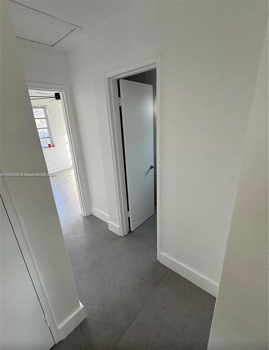 A hallway with gray tile flooring leads to a doorway and an adjacent room — 110 NW 120 Ter # 0, North Miami FL 33168, NORTH MIAMI, FL