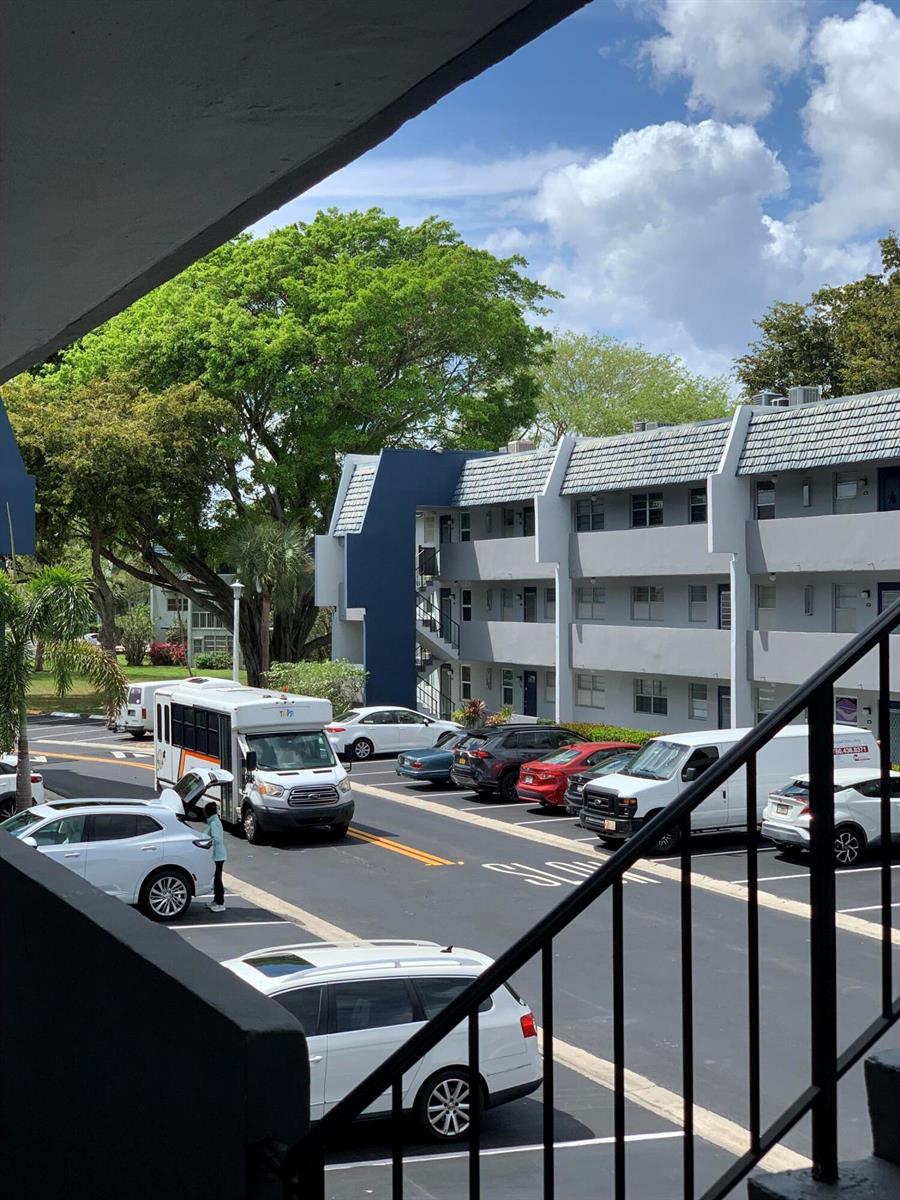 A view from an elevated walkway overlooking a parking lot with cars and a shuttle bus — 7887 Golf Cir Drive # 212, Margate FL 33063, MARGATE, FL