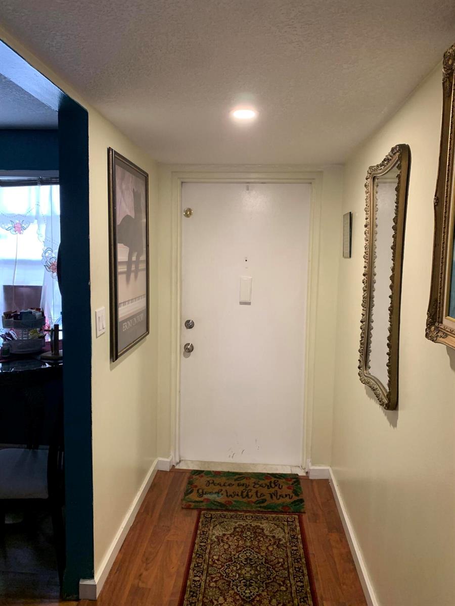 A narrow entryway features a white door, wood flooring, a runner rug, and wall mirrors — 7887 Golf Cir Drive # 212, Margate FL 33063, MARGATE, FL