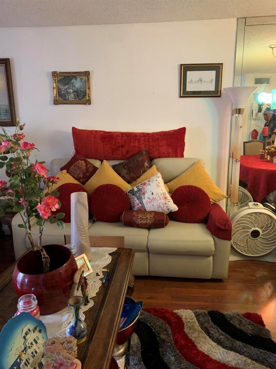 A living room features a beige sofa decorated with numerous red and yellow accent pillows — 7887 Golf Cir Drive # 212, Margate FL 33063, MARGATE, FL