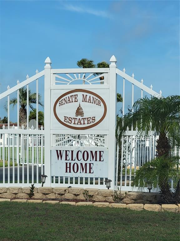 A white metal gate features a sign for Senate Manor Estates with a welcome banner — 10932 UNION DRIVE, PORT RICHEY, FL