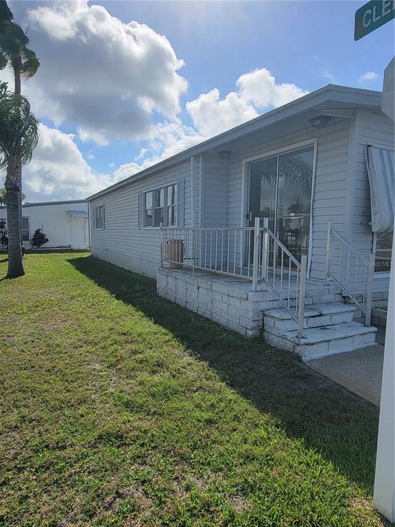 A light-colored mobile home features a raised concrete porch with a metal railing — 10932 UNION DRIVE, PORT RICHEY, FL
