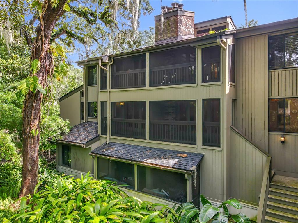 The exterior of a multi-story house features screened-in balconies, wood siding, and a brick chimney — 542 S OSCEOLA AVENUE UNIT 34, ORLANDO, FL