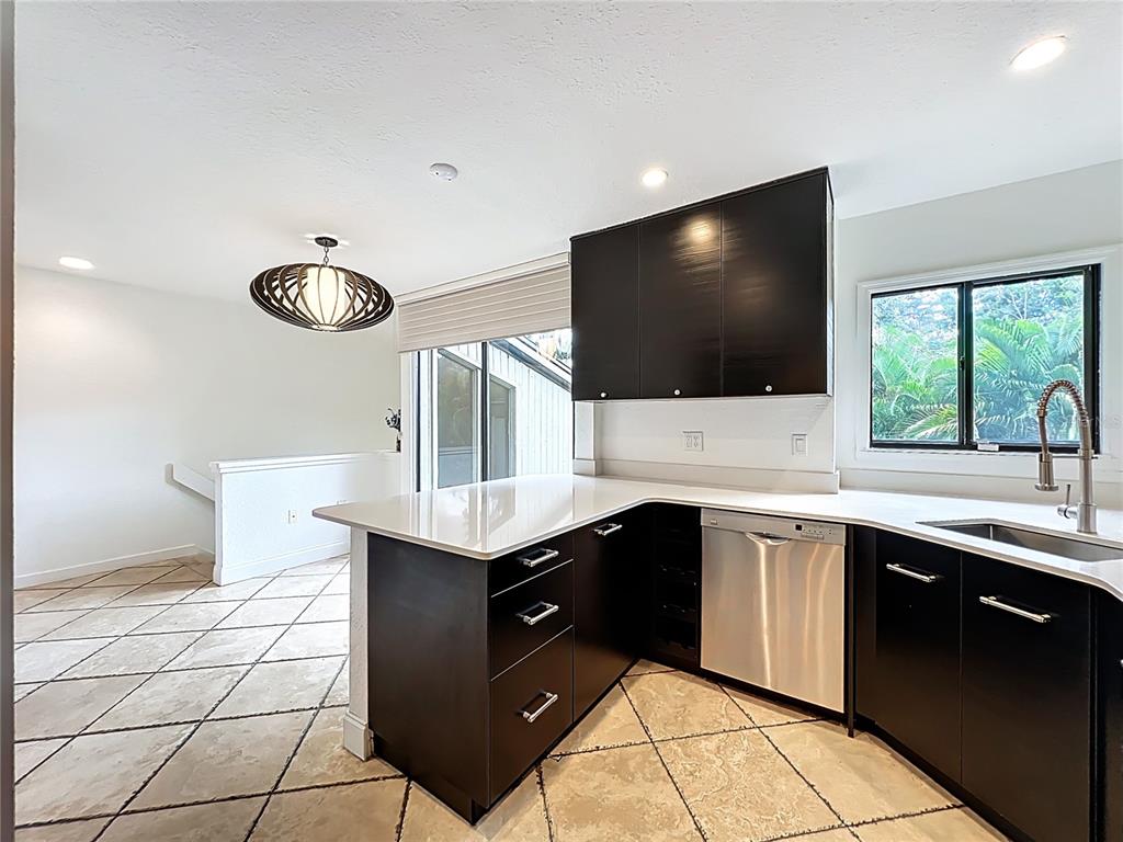 A kitchen features dark cabinets, white countertops, stainless steel appliances, and tile flooring — 542 S OSCEOLA AVENUE UNIT 34, ORLANDO, FL