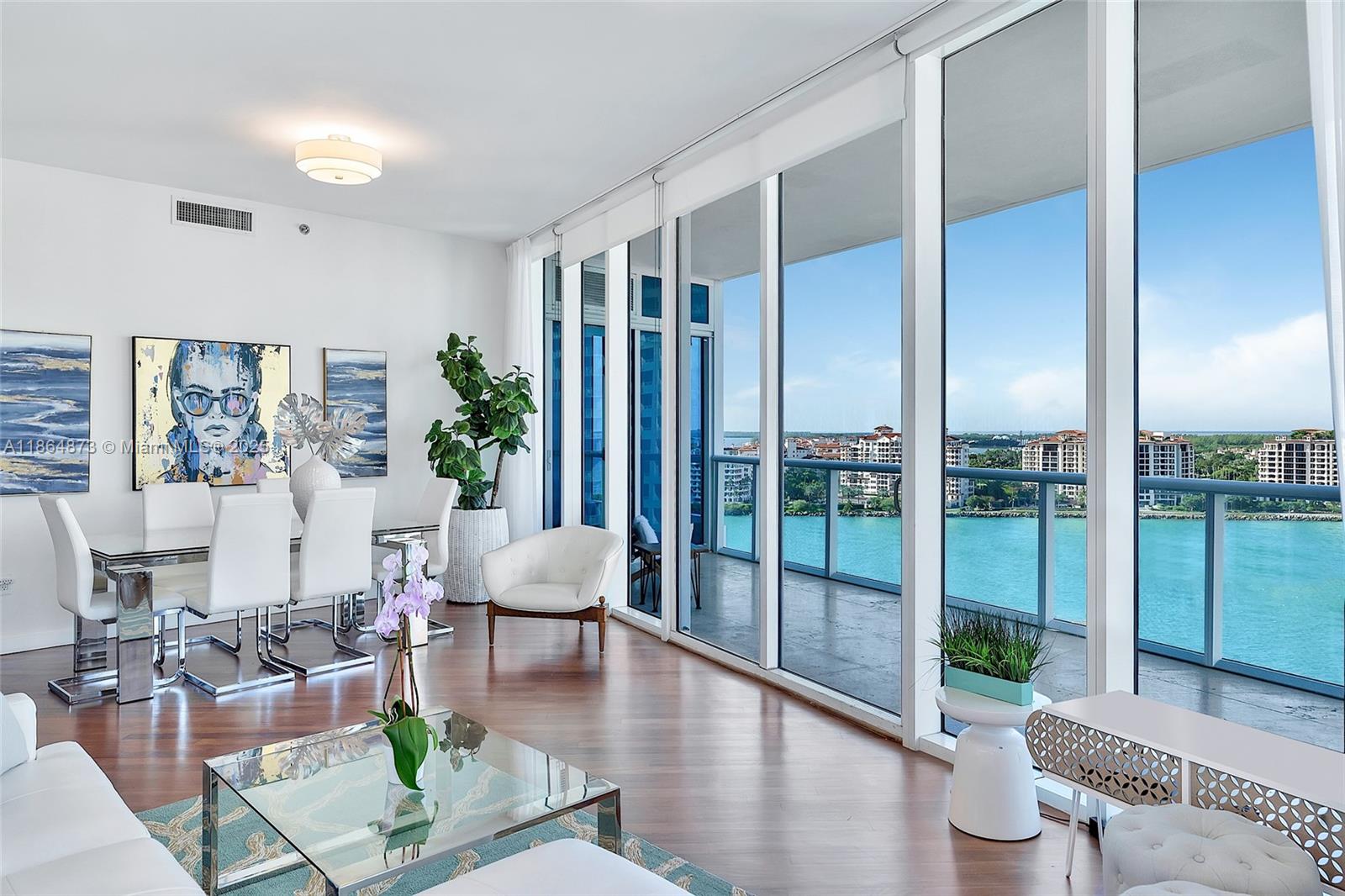 A modern living and dining area features floor-to-ceiling windows overlooking a bay and city skyline — 100 S Pointe Dr # 1501, Miami Beach FL 33139, MIAMI BEACH, FL