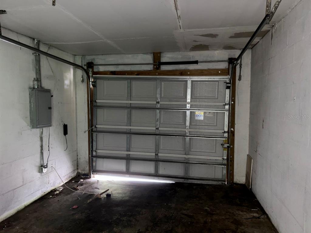 An interior view of a garage featuring a sectional metal door and exposed concrete walls — 2703 1ST AVENUE E, PALMETTO, FL