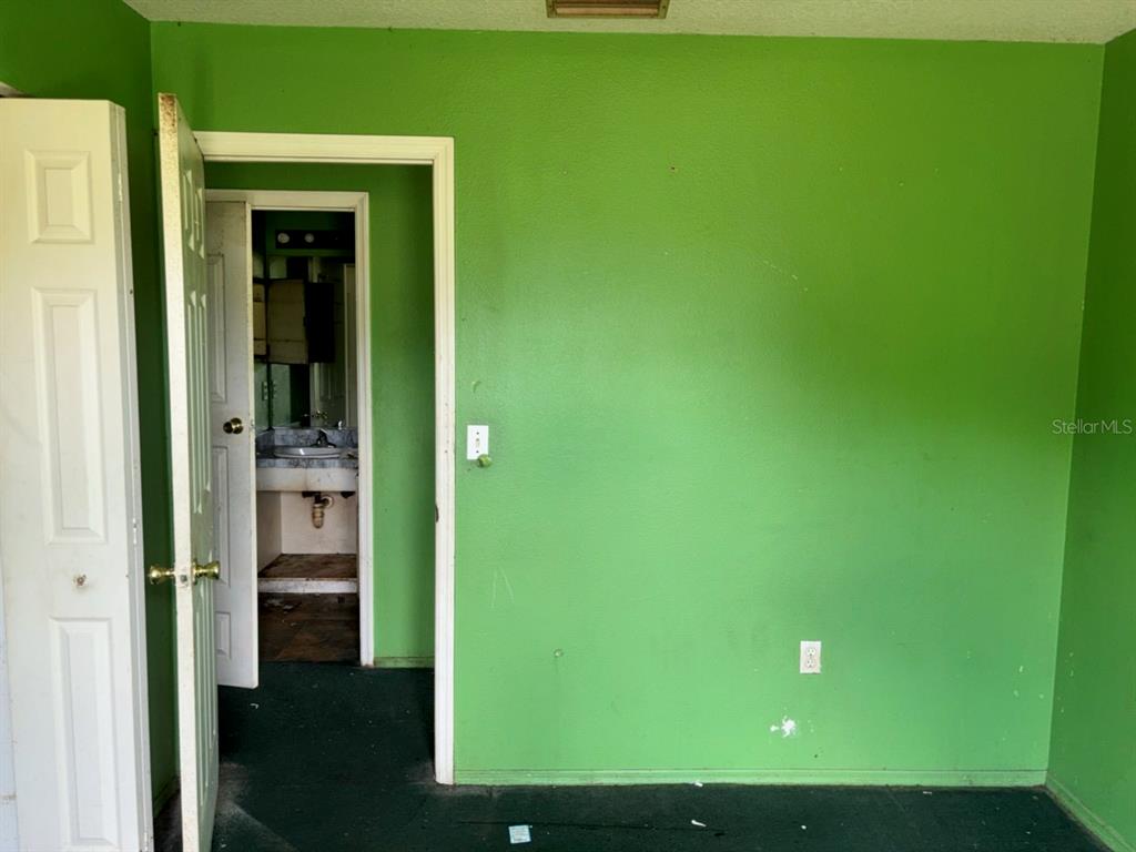 A room with bright green walls and a doorway leading to a small bathroom — 2703 1ST AVENUE E, PALMETTO, FL