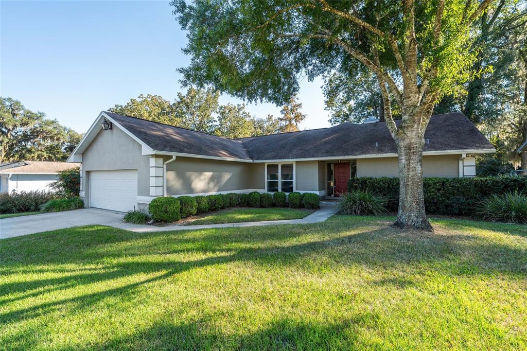 A single-story house with a beige exterior, a two-car garage, and a red front door — 8120 NW 48TH LANE, OCALA, FL
