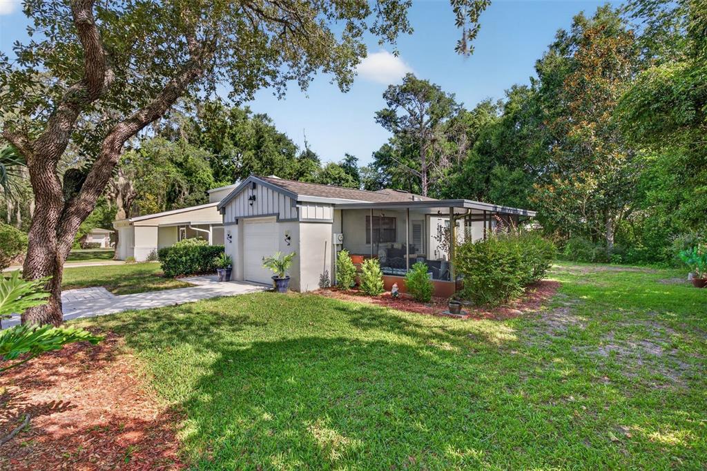 A single-story house with a white garage, a screened-in porch, and a large grassy yard — 12 CHINABERRY CIRCLE, HOMOSASSA, FL