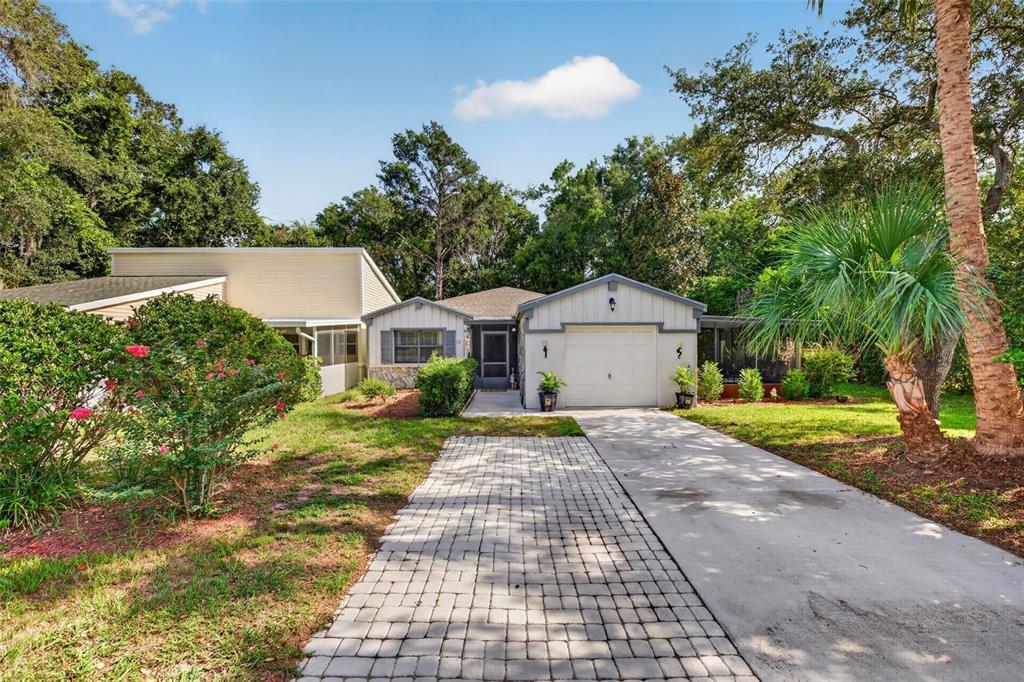 A single-story house with a paved driveway, a garage, and a screened-in front porch — 12 CHINABERRY CIRCLE, HOMOSASSA, FL