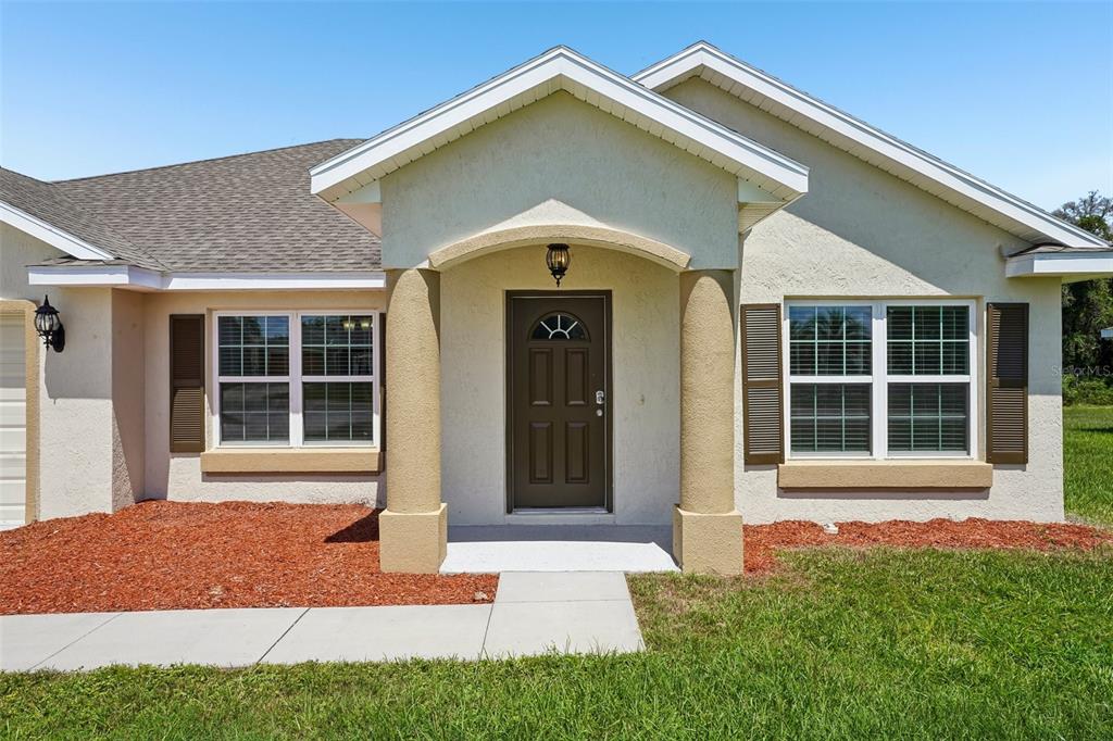 The exterior of a single-story house features a covered entryway with two columns — 387 MARION OAKS LANE, OCALA, FL