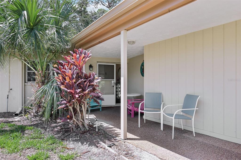 A covered patio features two chairs, a small table, and a large tropical plant — 7172 GREY SQUIRREL BOULEVARD UNIT 81, SARASOTA, FL