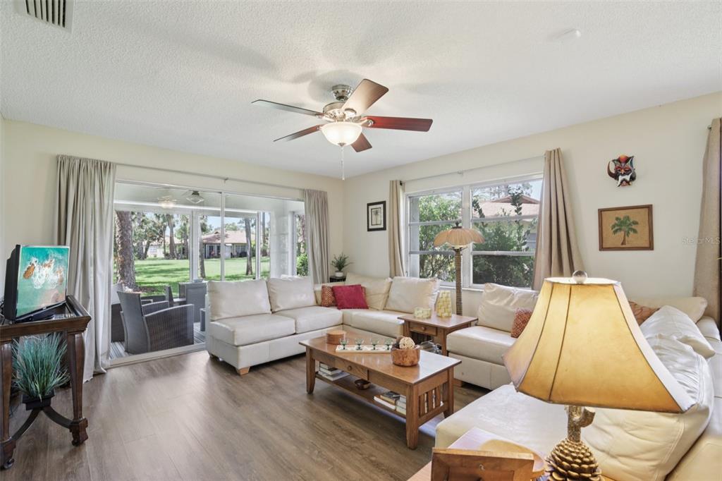 A living room features a white sectional sofa, wood coffee table, and sliding glass doors — 7172 GREY SQUIRREL BOULEVARD UNIT 81, SARASOTA, FL