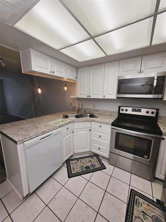 A kitchen with white cabinets, stainless steel appliances, and speckled laminate countertops — 1781 SAMURAI POINT UNIT P9, LUTZ, FL