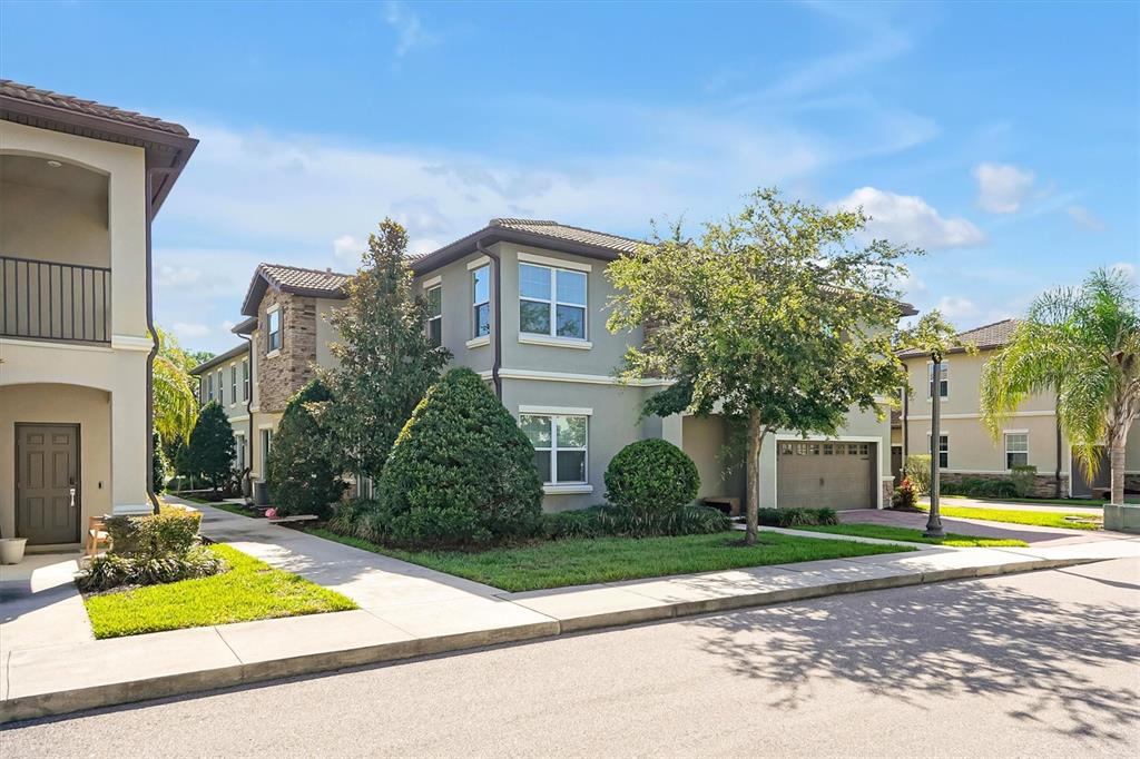 A two-story residential building with a tan stucco exterior, tile roof, and attached garage — 1383 SHINNECOCK HILLS DRIVE, DAVENPORT, FL