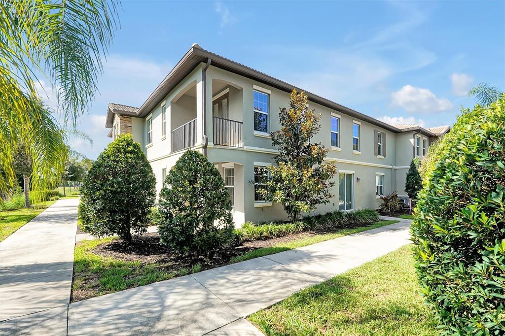 A two-story apartment building exterior with a balcony, tan stucco walls, and surrounding landscaping — 1383 SHINNECOCK HILLS DRIVE, DAVENPORT, FL