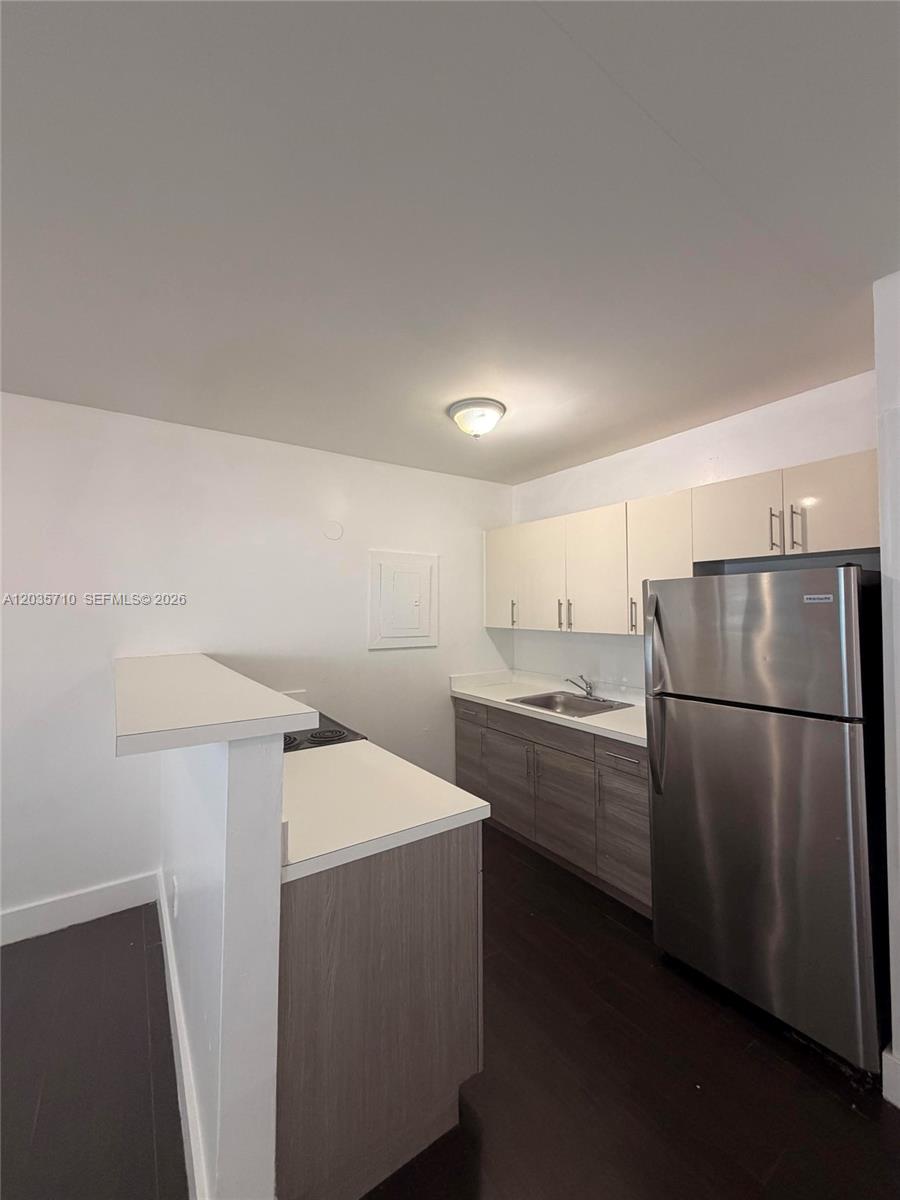A kitchen features white upper cabinets, wood-grain lower cabinets, stainless steel appliances, and a breakfast bar — 1040 NW 3rd Ave # 5, Miami FL 33136, MIAMI, FL