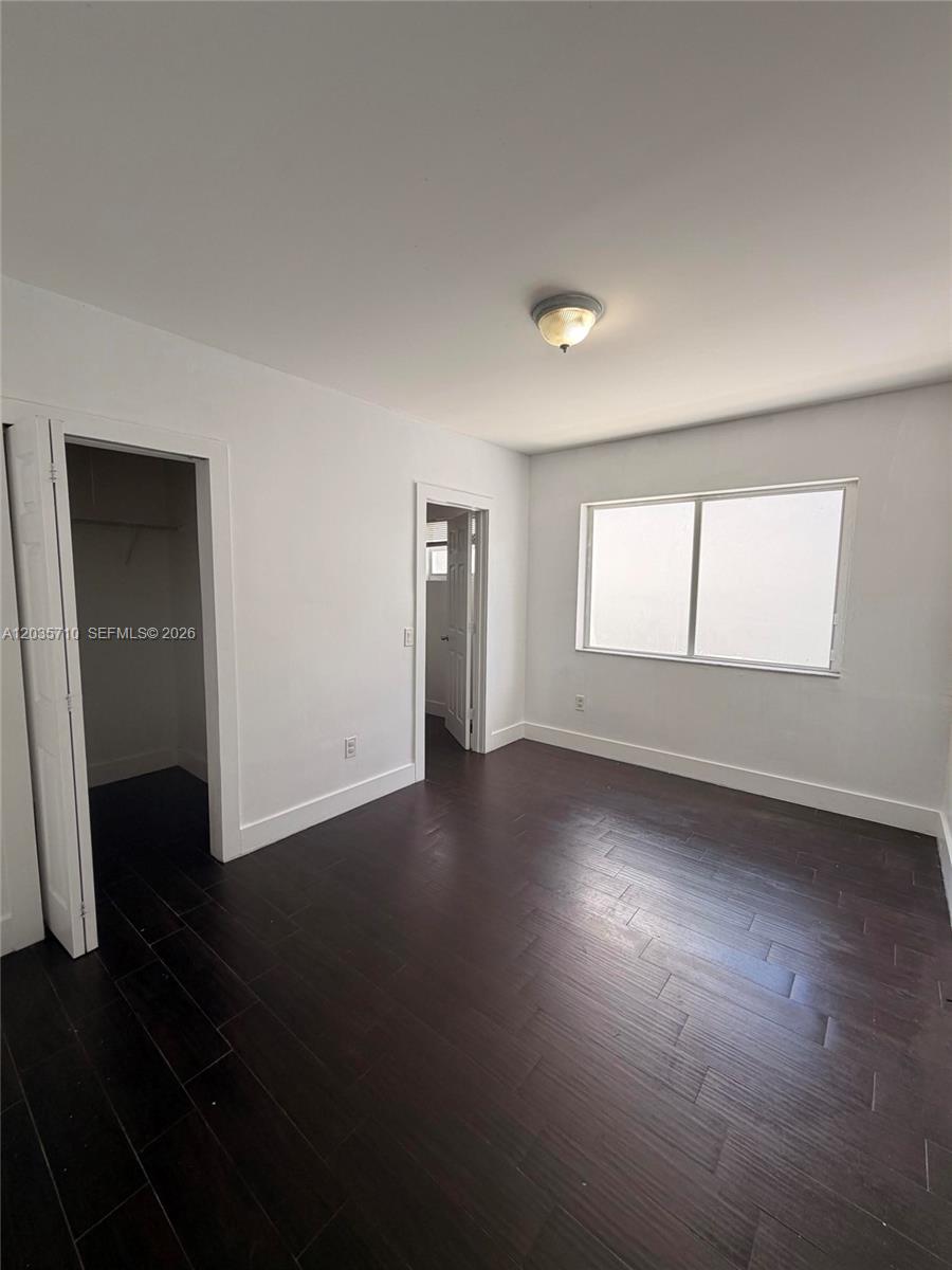 A bedroom features white walls, dark wood flooring, a closet, and a single window — 1040 NW 3rd Ave # 5, Miami FL 33136, MIAMI, FL
