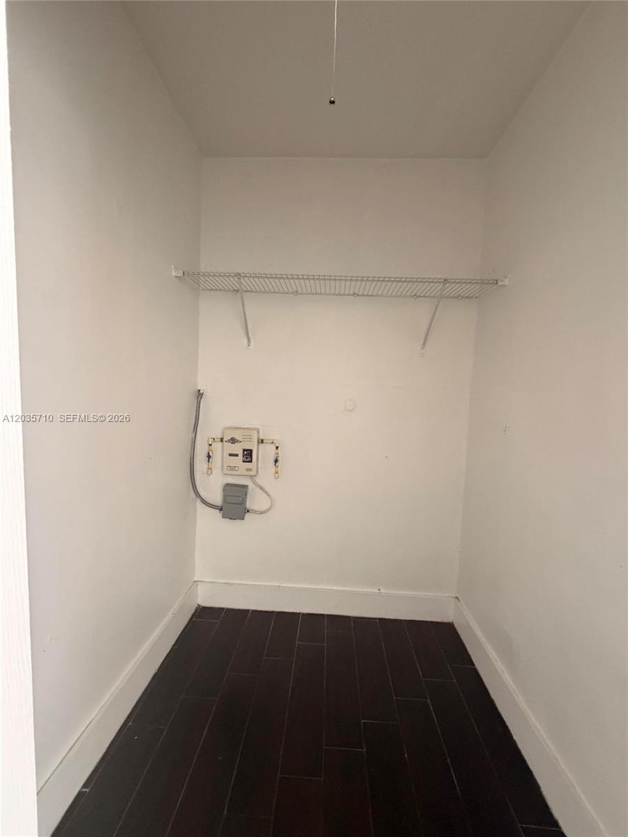 A small laundry closet features dark wood-look flooring, white walls, and a wire shelf — 1040 NW 3rd Ave # 5, Miami FL 33136, MIAMI, FL